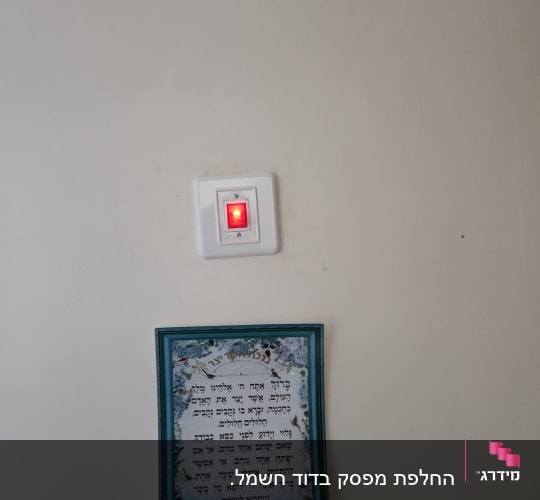 מתג דולק עם אור אדום על קיר לבן